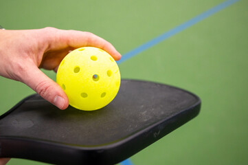 holding a pickle ball with hand