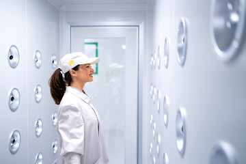 Factory worker standing in industrial air blowing tunnel removing dust and particles before entering production line.