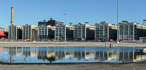 view of industry city buildings on 2nd avenue in sunset park brooklyn (reflection in the water) warehouse industrial buildings converted to retail and restaurants - obrazy, fototapety, plakaty