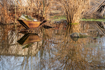 Spring landscape with vintage one wheeled cart and melt water. Spring flood.