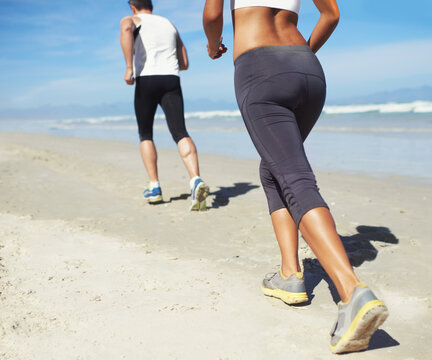 Running, beach and man with woman, fitness and cardio with workout and training for wellness. Healthy, runner and athlete with practice and vacation with water and waves with sunshine or getaway trip © peopleimages.com