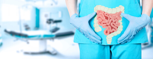 Close-up of a female surgeon doctor in a medical uniform and an icon of the intestine with a large intestine on the background of the operating table in the hospital, soft blurred background.