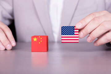 USA and China trade war, conflict of interest. Flags of America and China on wooden cubes in a businessman's hand.