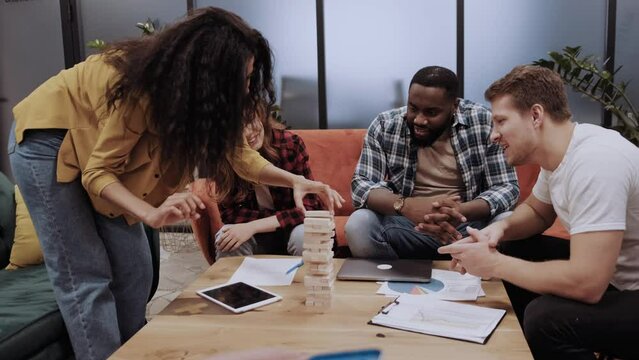 multiethnic employees in a modern office having fun with board games having fun