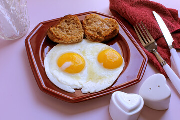 Valentine breakfast: eggs, sunny side up, with heart shaped, toasted English muffins.