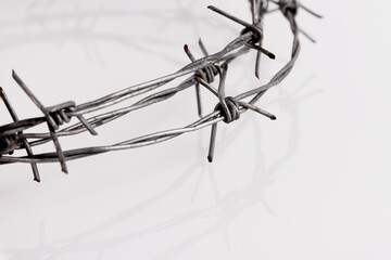 Barbed wire on a white background. Close-up, with sharp spikes arranged in a semicircle with...