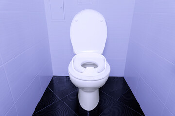 Baby toilet seat, toilet bowl workplace in restroom with black tiled floor and purple walls.