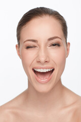 Portrait, smile and woman wink for skincare, flirt or beauty makeup isolated on white studio background. Face, blink and happy model in cosmetics excited for spa facial treatment for healthy skin