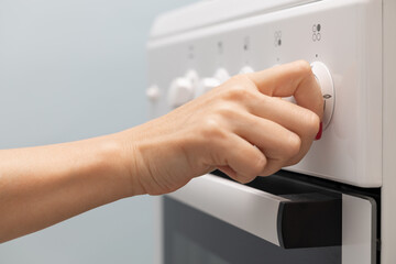 a woman's hand rotates the selector on a gas stove.