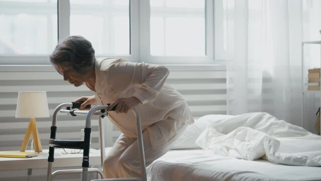 Senior woman navigates bedroom with folding walker, loneliness in elderly issue