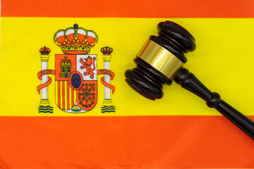 Justice in Spain. A judge’s gavel rests on the vibrant Spanish flag, symbolizing the country’s legal system