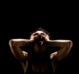 Portrait of a screaming woman in the shadow, hold her head , closed eyes on a black background