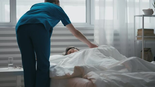 Nurse ensures comfort for bed-bound elder with blanket, professional home care