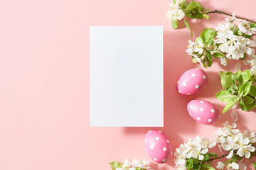Mockup invitation or blank greeting card with spring flowers and easter eggs on a pink background