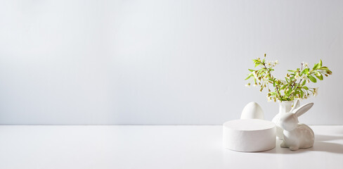 Empty round white podium for product presentation. Spring flowers in a vase and easter eggs on a light background - obrazy, fototapety, plakaty