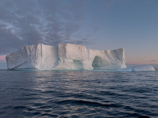 A huge high breakaway glacier drifts in the southern ocean off the coast of Antarctica at sunset,...
