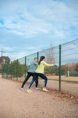 Active Couple in Athletic Wear Stretching Together Outdoors