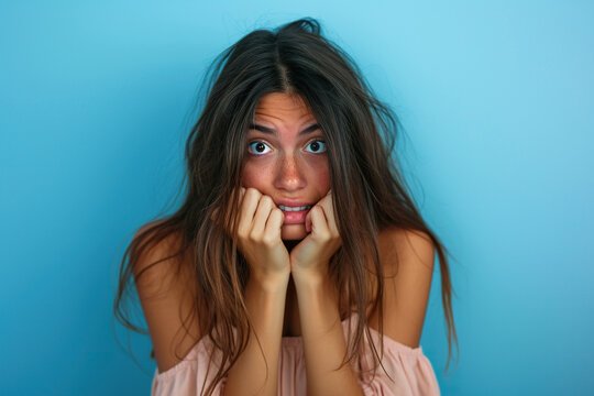 Nervous Latin woman in studio with oops reaction to gossip on blue background. Mistake, sorry and female overwhelmed by fake news