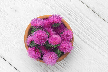 Silybum marianum (milk thistle) flowers in a wooden bowl.One of the most common uses of milk...