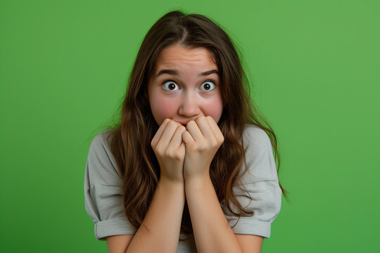 Nervous teenager girl in studio with oops reaction on green background. Mistake, sorry, drama or secret with regret, shame or awkward