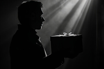 A visually striking and dramatic silhouette of a person holding a perfectly presented gift.