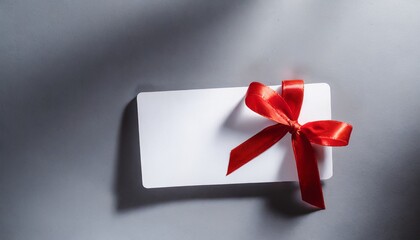 blank white gift voucher with red ribbon bow or empty gift signboard on grey background with shadow minimal conceptual