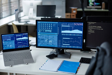 Background image of several computers on desk in cybersecurity department with blue data charts copy space