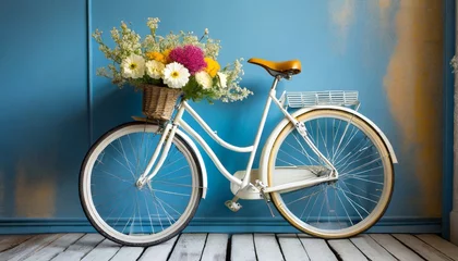 Tuinposter Fiets front wheel of bicycle with flowers in basket in front of blue wall