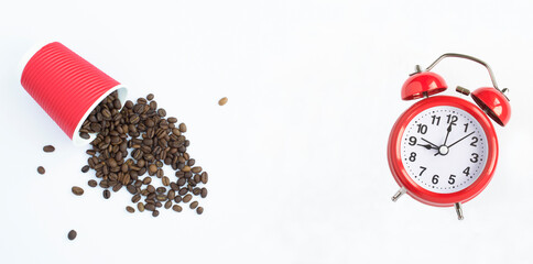 Disposable red paper cup with coffee beans and red alarm clock on the white background. Top view. Copy space.