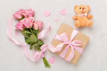Pink roses with hearts and gift box on concrete background, top view. Valentines day concept