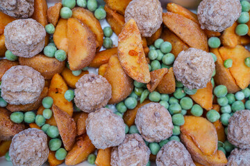 Frozen lunch in a baking dish potato slices, meatballs and green peas