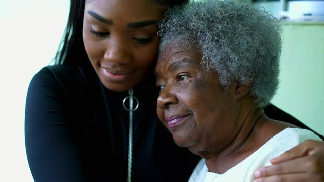 Affectionate Embrace of African American Grandmother by Teenage Granddaughter, inter-generational family member taking care of senior wrinkled woman with gray hair in 80s