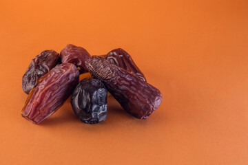 A pile of date fruits on an orange background. A staple of iftar time during Ramadan. Space for text