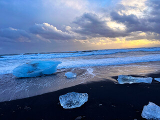 Icebergs looking like diamonds at world famous diamond beach on a day with a lovely sunset in...