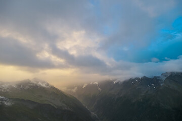 Panoramic view from mountain peak Arnoldhoehe in Ankogel Group, High Tauern National Park, Austria. Wanderlust in untamed snow covered Austrian Alps. Cloud covered terrain in idyllic hiking atmosphere
