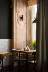 Cafe interior: small tables near tiled wall and window. Empty cafe, designed in classic style.