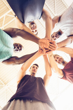 Men in team huddle with hands together in gym