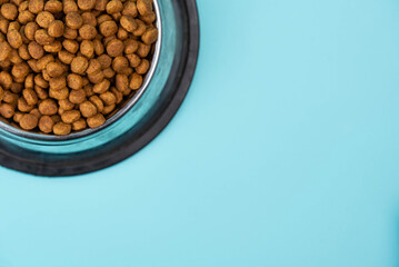 Brown cat or dog kibble in a metal bowl isolated top view close-up. Nutritious healthy diet pet...