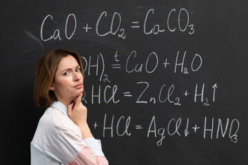 A student tired of complex chemistry stands near the blackboard and tries to understand chemical...