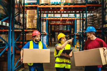 Workers in safety gear checking inventory in warehouse