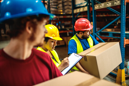 Workers in safety gear checking inventory in warehouse