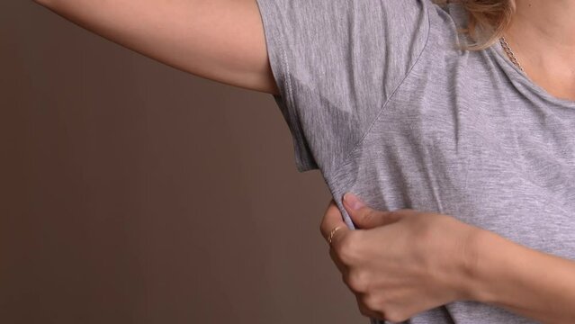 Woman with problem of sweat under her armpits. Concept smells bad. Hyperhidrosis. sweating and agitation. Close-up of spot with hyperhidrosis of sweating under armpit. Concept of health care.