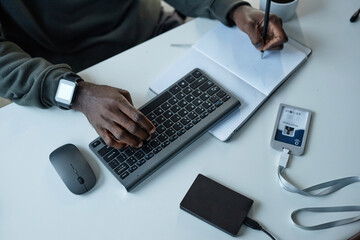 High angle closeup of unrecognizable Black man using computer in office male hands typing at...