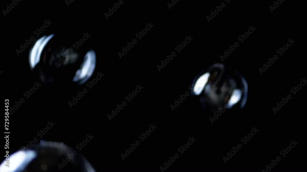 Poster colorful soap bubbles fly in an empty space on isolated black background. many large, small rainbow 