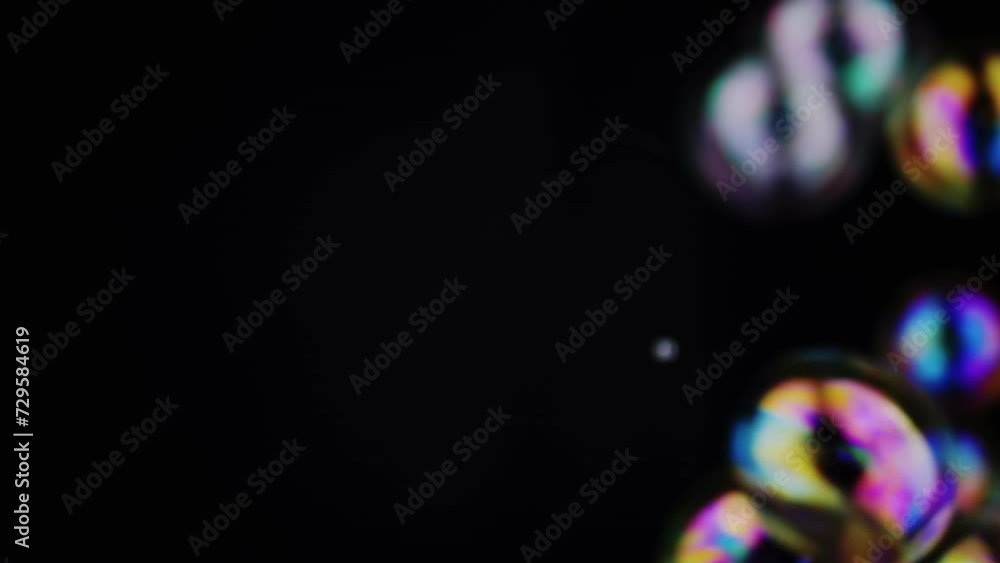 Poster colorful soap bubbles fly in an empty space on isolated black background. many rainbow transparent b