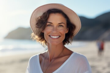 Portrait of a beautiful happy smiling middle aged woman wearing a hat on the beach on a sunny day. AI Generated