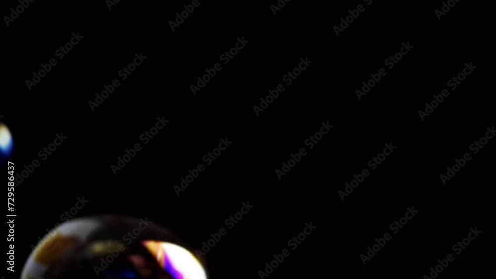Poster colorful soap bubbles fly in an empty space on isolated black background. many large, small rainbow 
