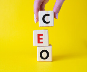 CEO - Chief executive officer symbol. Concept word CEO on wooden cubes. Businessman hand. Beautiful yellow background. Business and CEO concept. Copy space.