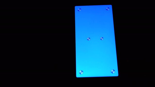 Smartphone with a Blue Screen Rotates on a Black Background in the Dark Room. Empty space, a place for text. Markers. Gadget, a mobile phone with a glowing screen. Chrome kay background. Close up.