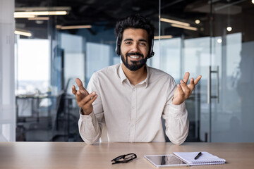 Indian businessman in office setting wearing headset and smiling confidently at work
